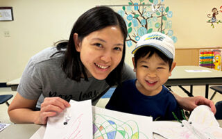 Parent and child showing off their artwork in Scribble Time.